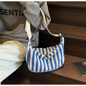 Détail du sac demi-lune en toile rayé bleu et blanc avec large bandoulière en sangle