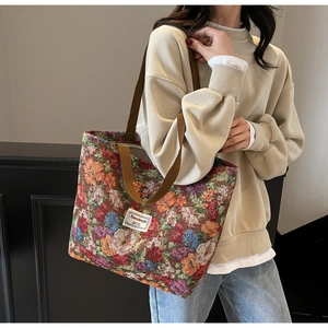 Détail du sac cabas en tapisserie florale avec anses tissées et étiquette de marque