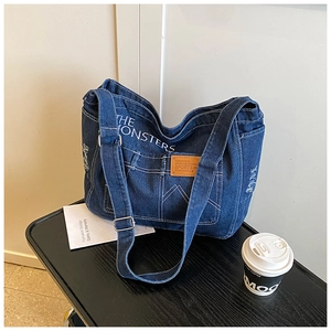 Detail of vintage denim tote bag with functional pockets and white contrast stitching