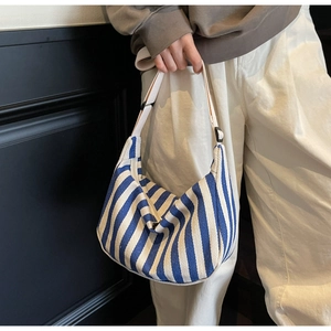 Détail d'un sac demi-lune en toile à rayures bleues et blanches avec bandoulière réglable
