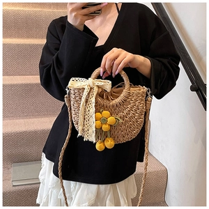 Détail du sac seau en paille avec fleurs au crochet jaunes et nœud en ruban dentelle