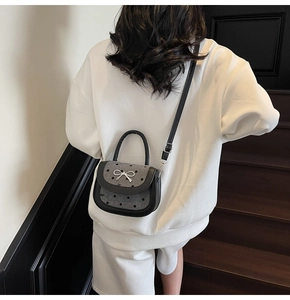 Detail of grey polka dot saddle bag with silver bow clasp and black leather trim