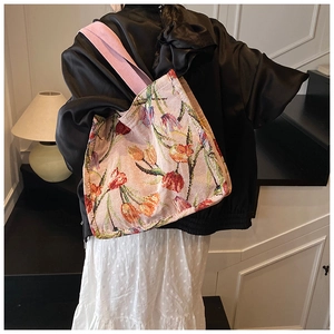 Dettaglio della borsa tote in maglia rosa con tulipani arancioni e tracolla larga