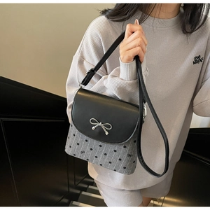 Detail of grey crossbody bucket bag with black polka dots and silver bow decoration