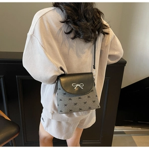 Detail view of the gray crossbody bucket bag with black bow print on a fashion model