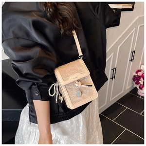 Detail of off-white small square bag with leaf texture and elegant pearl chain accessory