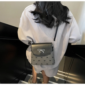 Detail of gray bow pattern fabric and silver metallic bow on a small crossbody bag
