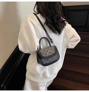 Rear view of a stylish bow knot saddle bag worn on a shoulder against modern stairs