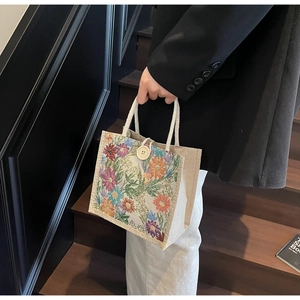 Detail of linen tote bag with floral tapestry panel and white rope handles