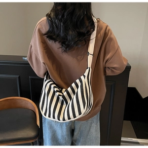 Détail de la bandoulière large réglable et du sac besace en toile rayée pour femme