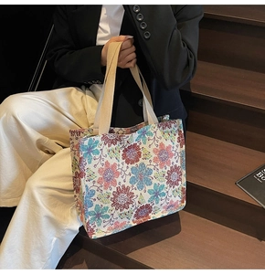Ethnic style floral canvas tote bag with woven handles shown in a lifestyle street setting