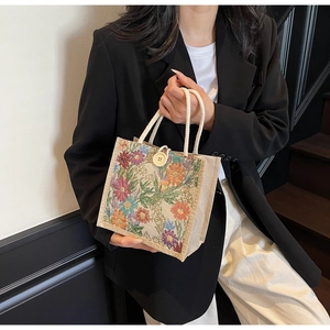 Detail of floral linen lunch bag featuring vintage embroidery and a wooden button closure