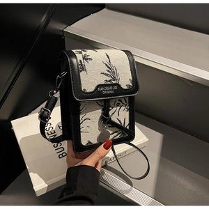Detail of canvas crossbody phone bag with black floral pattern and leather trim