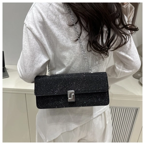 Detail of a black glitter crossbody bag with silver chain strap and metal clasp on shoulder