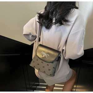 Chic grey and black bucket bag with silver bow ornament worn by model on stairs