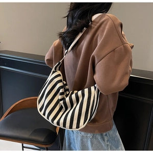 Détail du grand sac hobo en toile à rayures noires et blanches porté par un mannequin