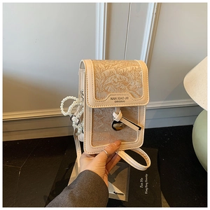 Detail of embossed leaf texture and pearl chain strap on the beige crossbody bag