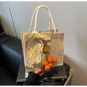 Detailed jute mini tote with large lace bow and colorful fruit charms, summer style bag