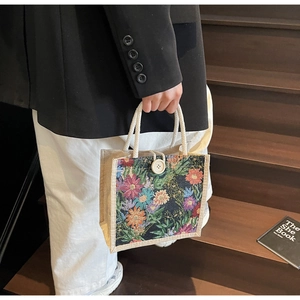 Detailed shot of floral tapestry jacquard tote with braided rope handles and button closure