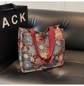 Detail of retro floral pattern jacquard fabric and red handles on a large tote bag