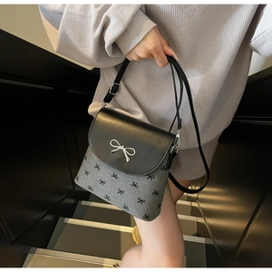 Close-up of contrast crossbody bag with silver bow buckle and printed ribbon pattern