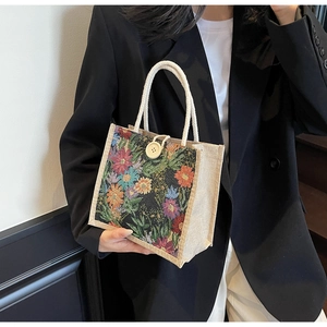 Close-up of floral embroidered linen tote bag with white cotton rope handles and button detail