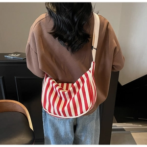 Sac bandoulière en toile à rayures rouges et blanches porté par un mannequin