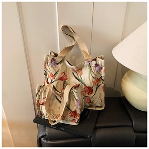 Dettaglio di due borse tote jacquard con motivi di tulipani e manici intrecciati