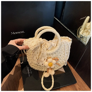 Détail du sac seau en paille tressé avec nœud en dentelle, breloque fleurie et cordon