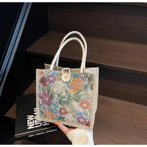 Close-up of ethnic floral woven linen tote bag with braided handles and button closure