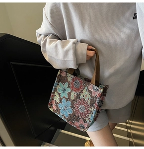 Detailed texture of ethnic floral tapestry tote bag with sturdy woven brown handles
