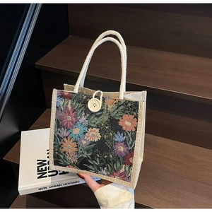 Close-up of floral tapestry tote with linen panels and thick rope handles on wooden stairs