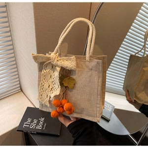 Detail of jute tote bag featuring delicate lace bow and cute pumpkin charms decoration