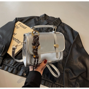 Detail of silver mirror leather handbag with gold buckles on a black leather jacket