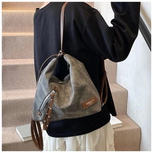 Close-up of grey matte tote bag featuring vintage leather patch and side zipper detail