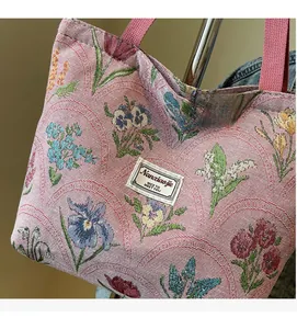 Close-up of floral jacquard fabric and brand label on a large canvas tote bag