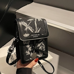 Chic black jacquard crossbody bag with floral pattern and silver charm on books