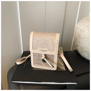 Detail of beige jacquard phone bag with leaf patterns and elegant pearl chain strap