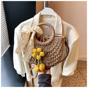 Détail du sac à main en paille avec nœud en dentelle et fleurs au crochet jaune
