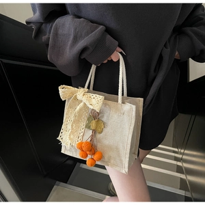 Detail of canvas handbag featuring white lace bow and plush orange pumpkin charm