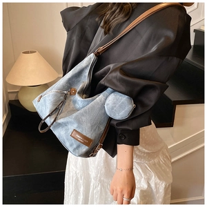 Detail of washed denim tote bag with brown leather straps and round coin pouch accessory