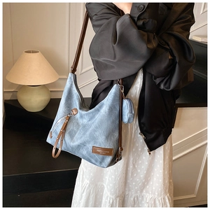Detail of light blue textured tote bag with brown leather labels and a matching round coin purse