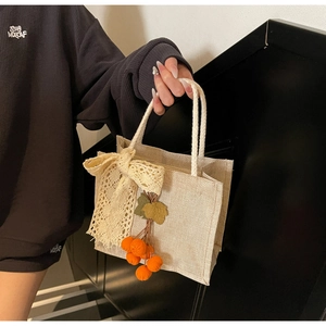 Detailed close-up of beige linen lunch bag with yellow lace bow and orange fruit charm