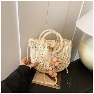 Détail d'un sac à main en paille avec nœud en dentelle et breloque florale