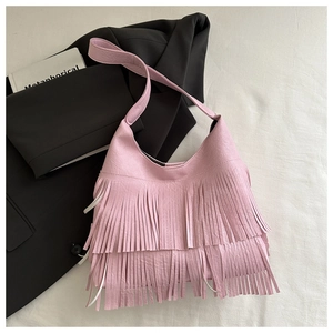 Close-up of pink hobo bag with bohemian fringe detail on a black blazer background