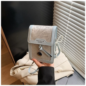 Detailed view of light blue crossbody bag with pearl chain and embossed fabric texture