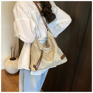 Detail view of large tote bag with washed canvas texture and brown leather strap details