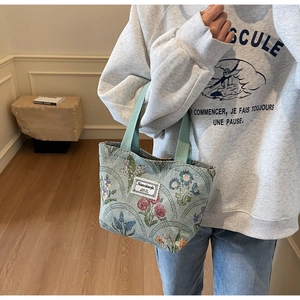 Close-up of floral jacquard tote bag featuring colorful flower patterns and green straps