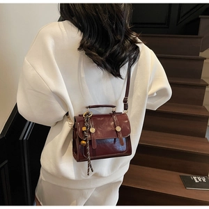 Detailed view of deep wine red leather crossbody bag with vintage gold clasp on model