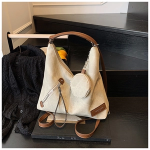 Detail of beige hobo bag with brown strap, front zipper, and round coin purse attachment